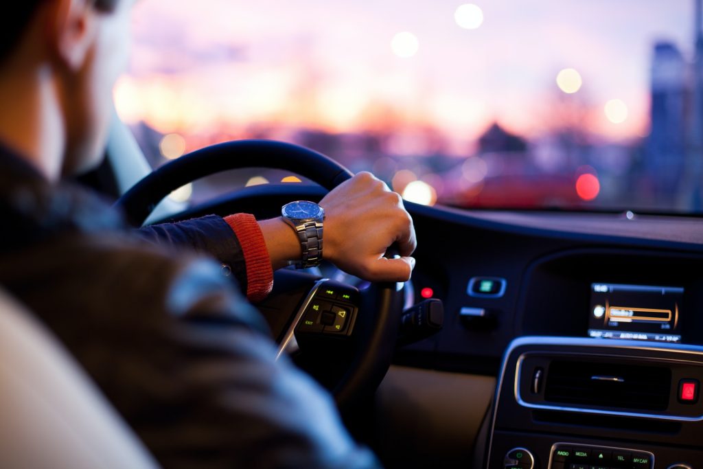 Man at the wheel of a car. Photo by why kei on Unsplash.