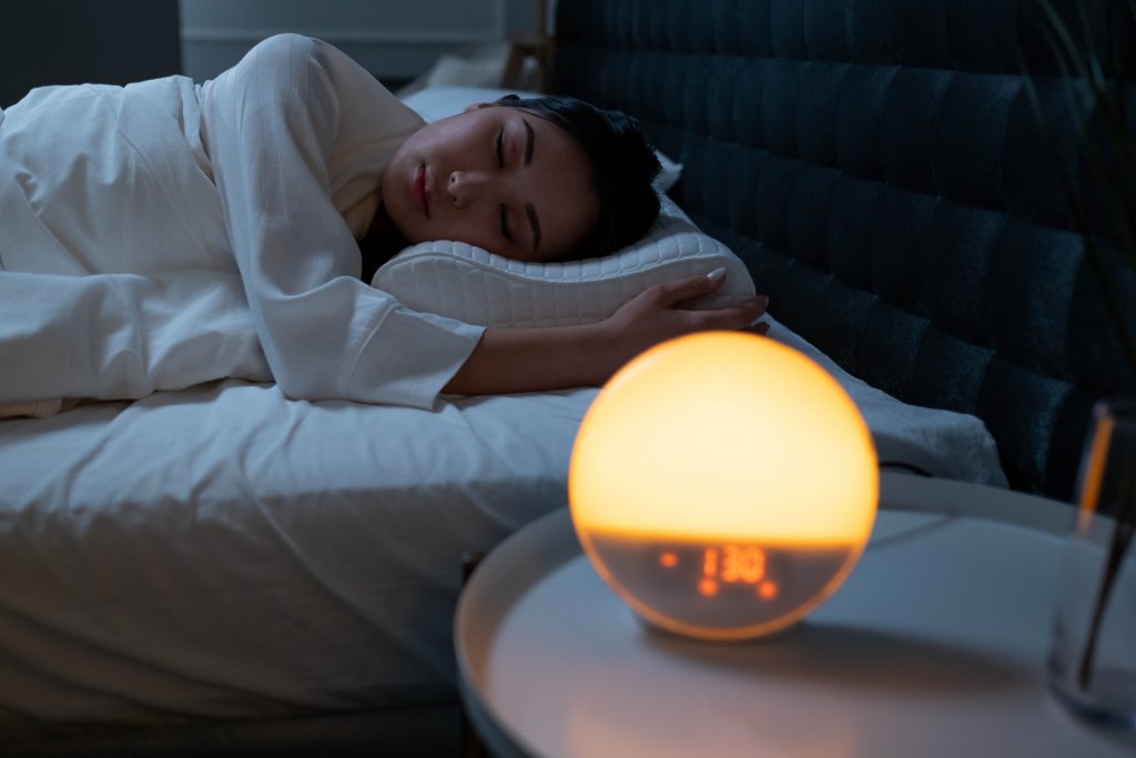 Woman sleeping with an alarm clock on bedside. Photo by cottonbro from Pexels